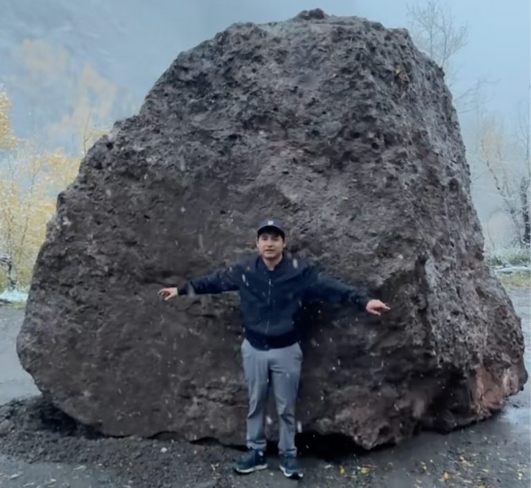 Francisco Sandoval stands in front of the boulder.